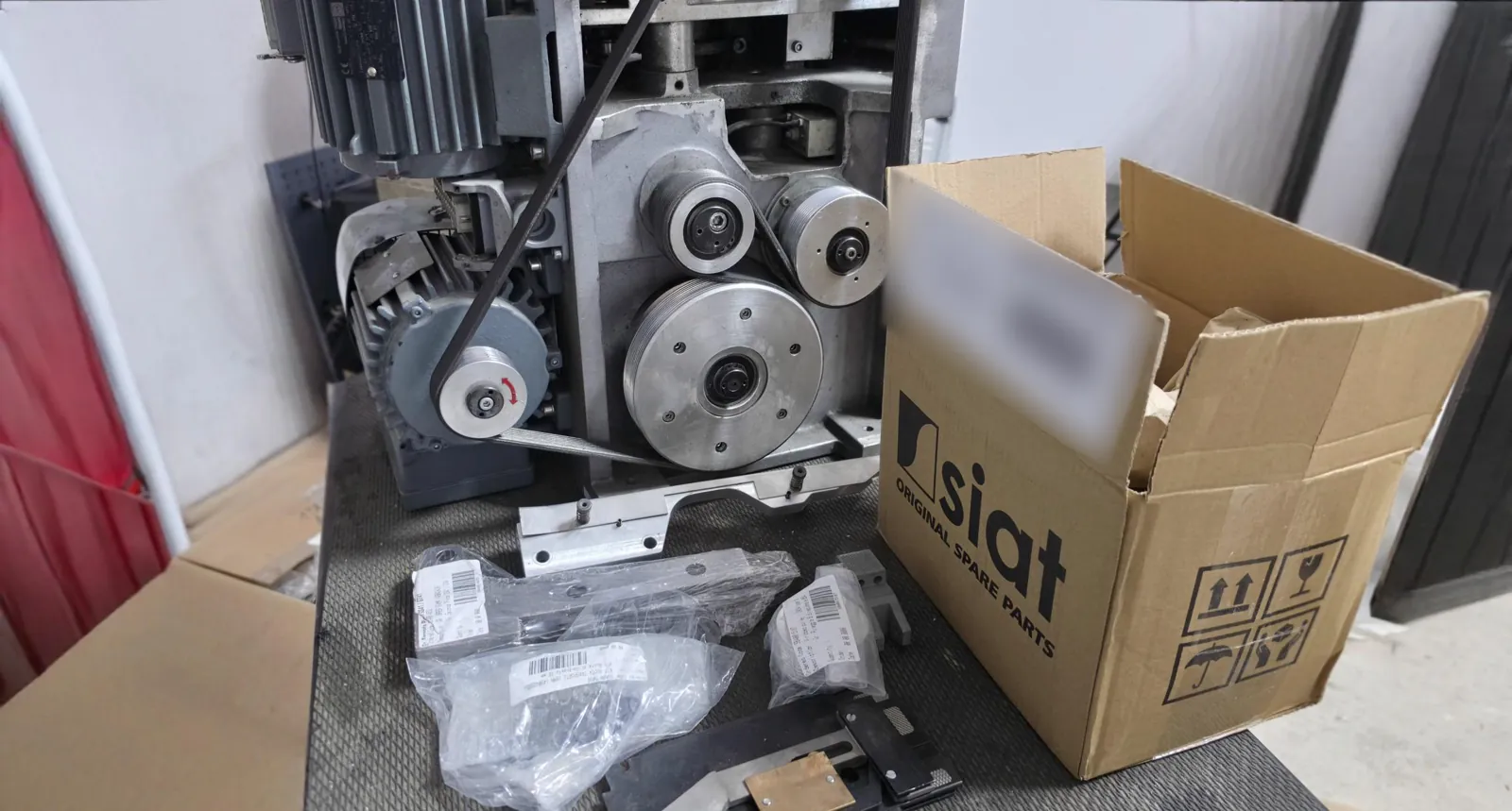 SIAT machine opened on our workshop bench, next to a box of original SIAT spare parts